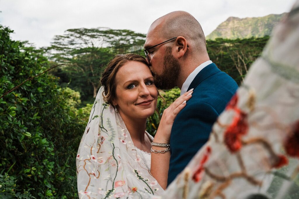 Groom kisses bride on the forehead during their elopement in Kauai 