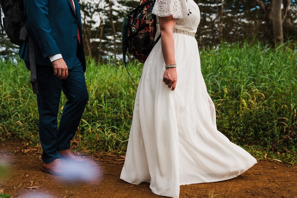 Bride and groom walk across a lush green trail during their elopement in Kauai 