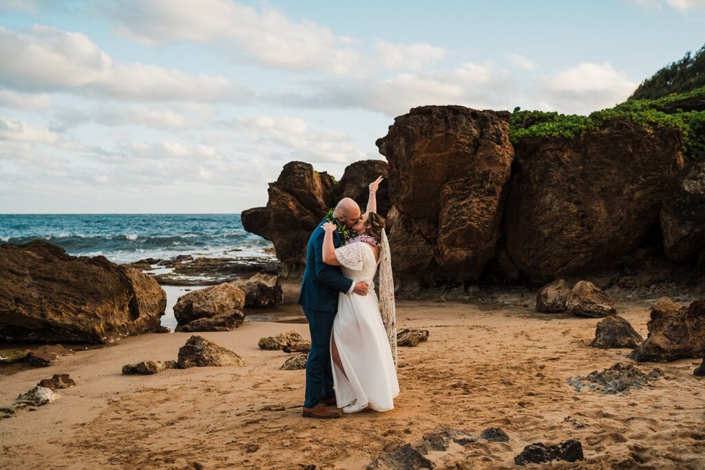 Bride and groom kiss during their Kauai Hawaii elopement ceremony on the beach 