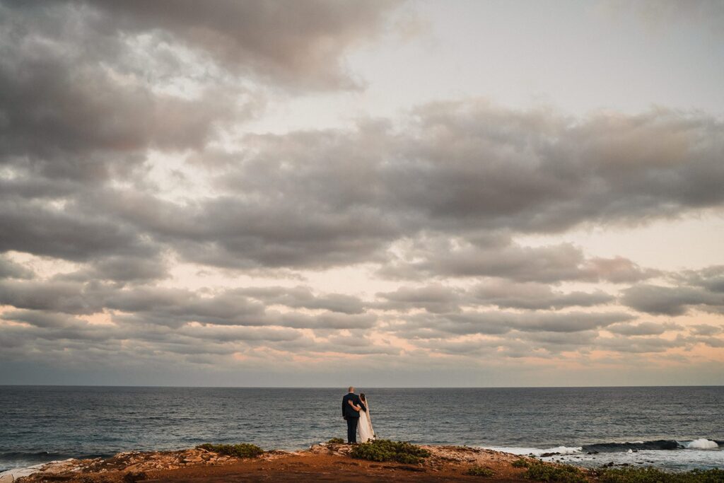 Bride and groom hug on the cliffs of Kauai during their sunset elopement 