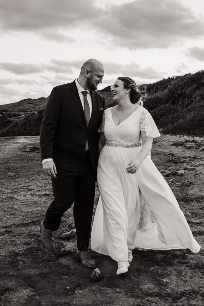 Bride and groom walk across a rocky beach during their sunset Kauai Hawaii elopement 