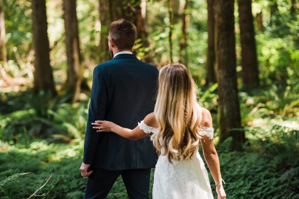 Bride taps groom on the arm for their elopement first look in the forest 