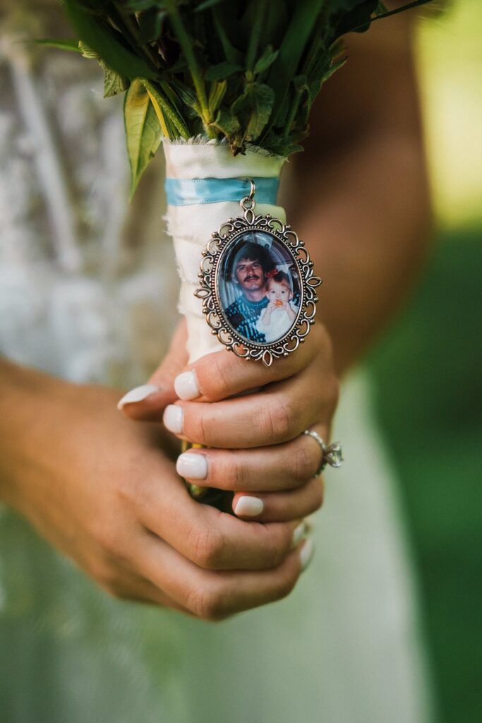 Picture locket hanging off bride's elopement flower bouquet 