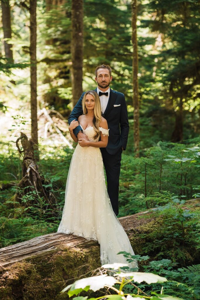 Bride and groom stand on a fallen log during their Mount Rainier National Park elopement photos 