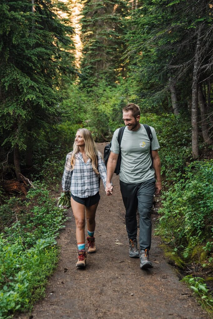 Bride and groom hold hands while hiking a mountain trail during their Mt Rainier National Park elopement 