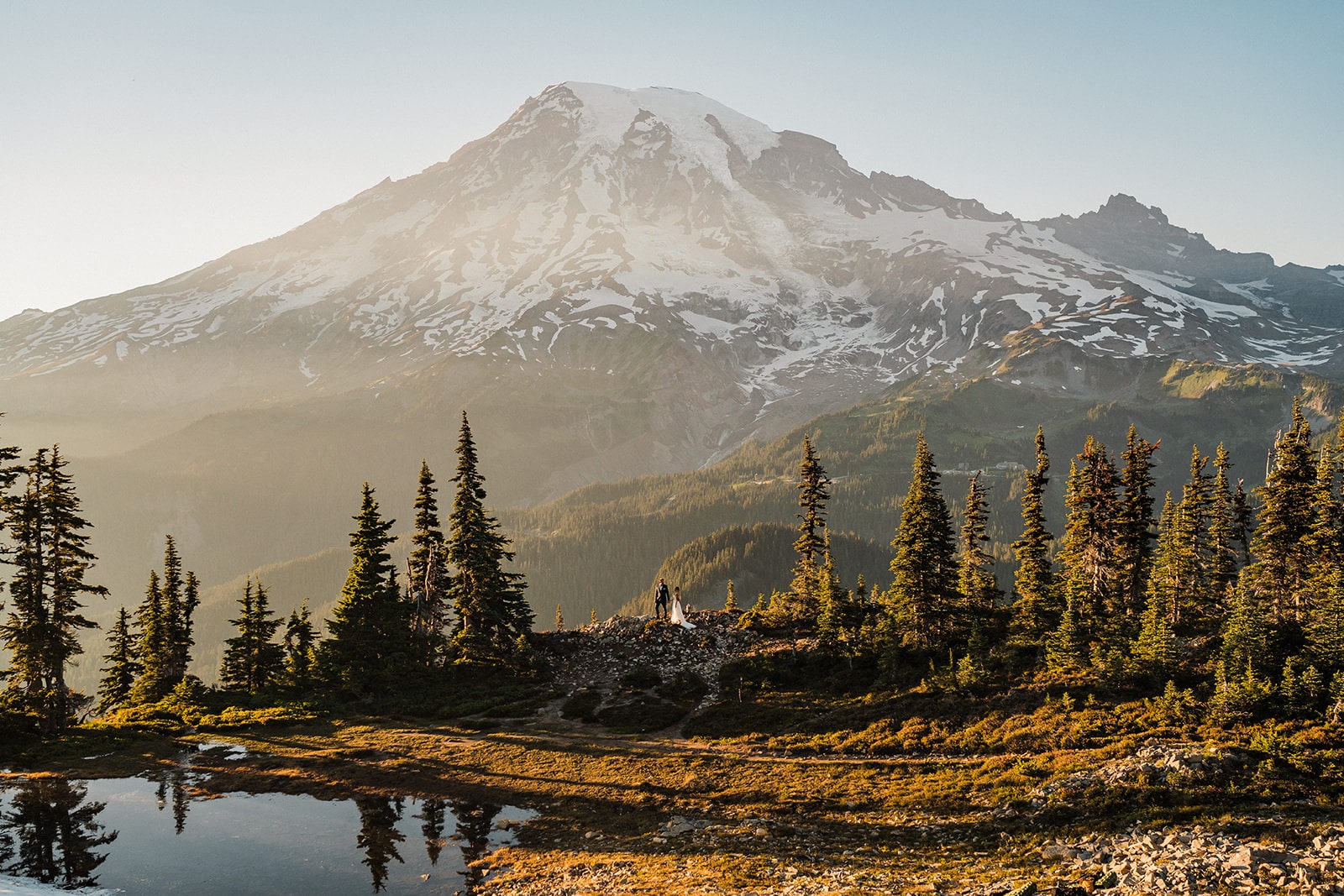 Bride and groom stand on a mountain trail in front of Mt Tahoma during their wedding at a national park