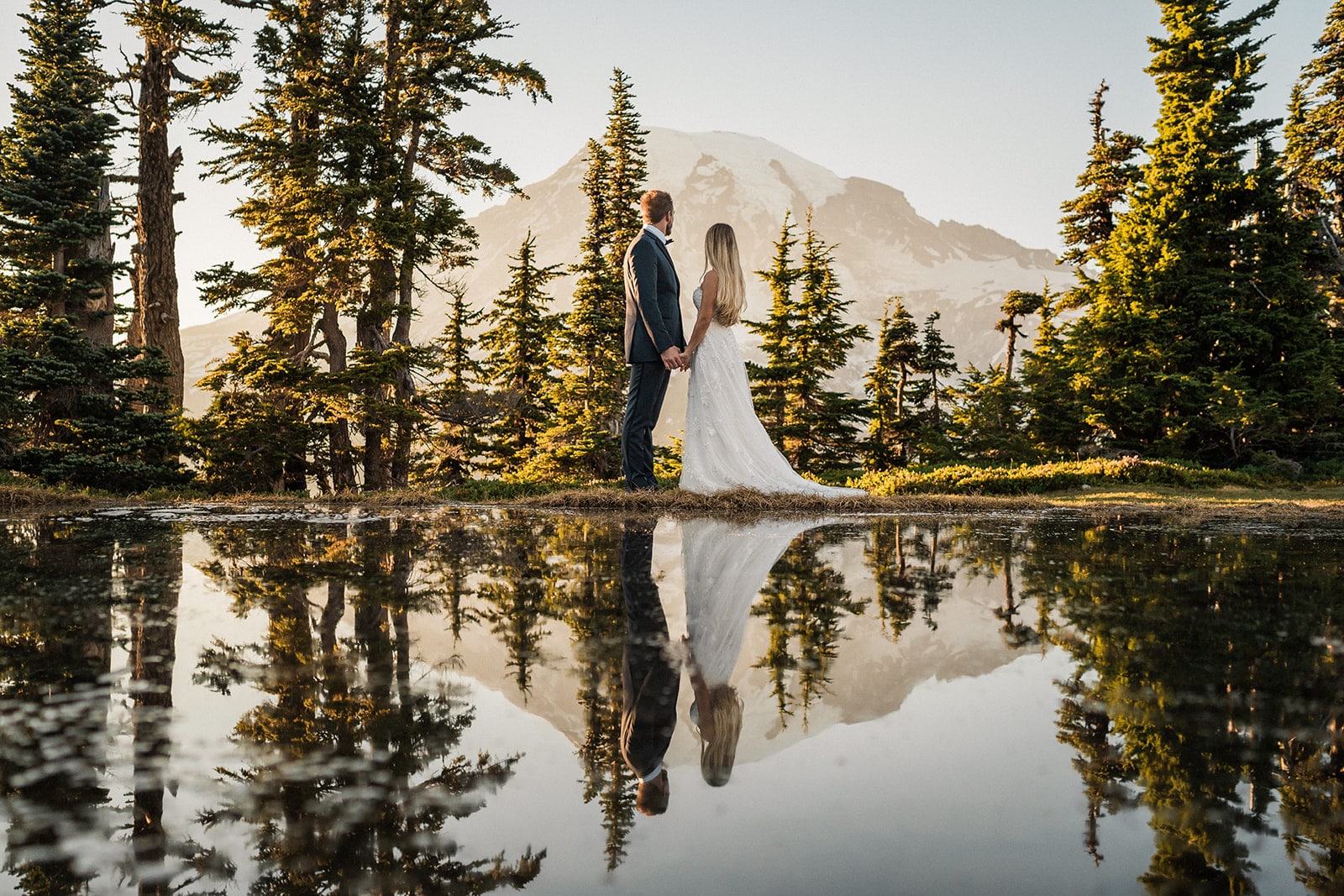 Bride and groom stand by an alpine lake during their microwedding adventure