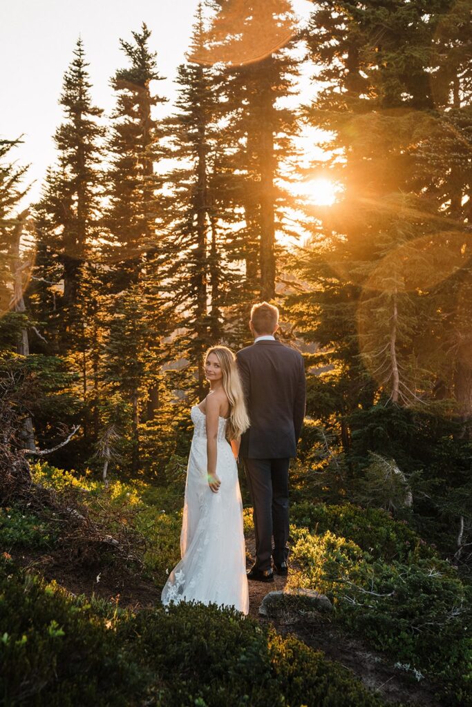 Bride and groom hold hands on a forested mountain trail at Mount Rainier National Park 