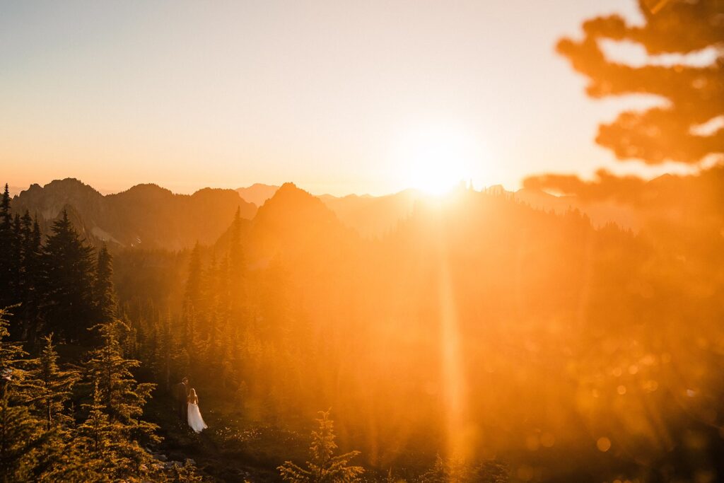 Bride and groom hug on a mountain trail at sunset at Mount Rainier National Park