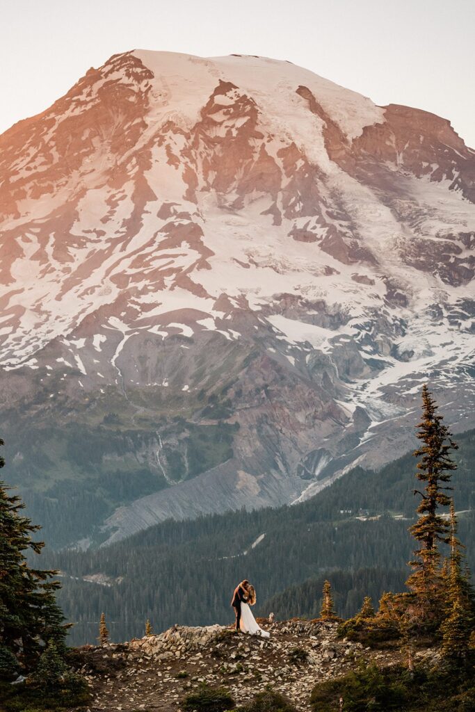 Bride and groom kiss on a mountain trail during their Mount Rainier National Park elopement