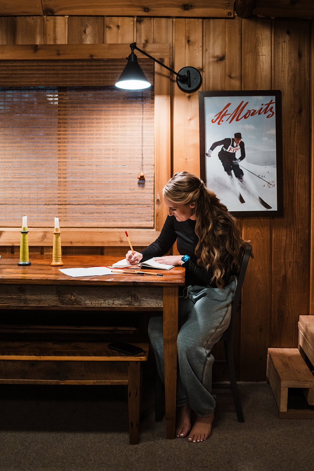 Bride sits at a wood table in her family cabin writing her personal wedding vows