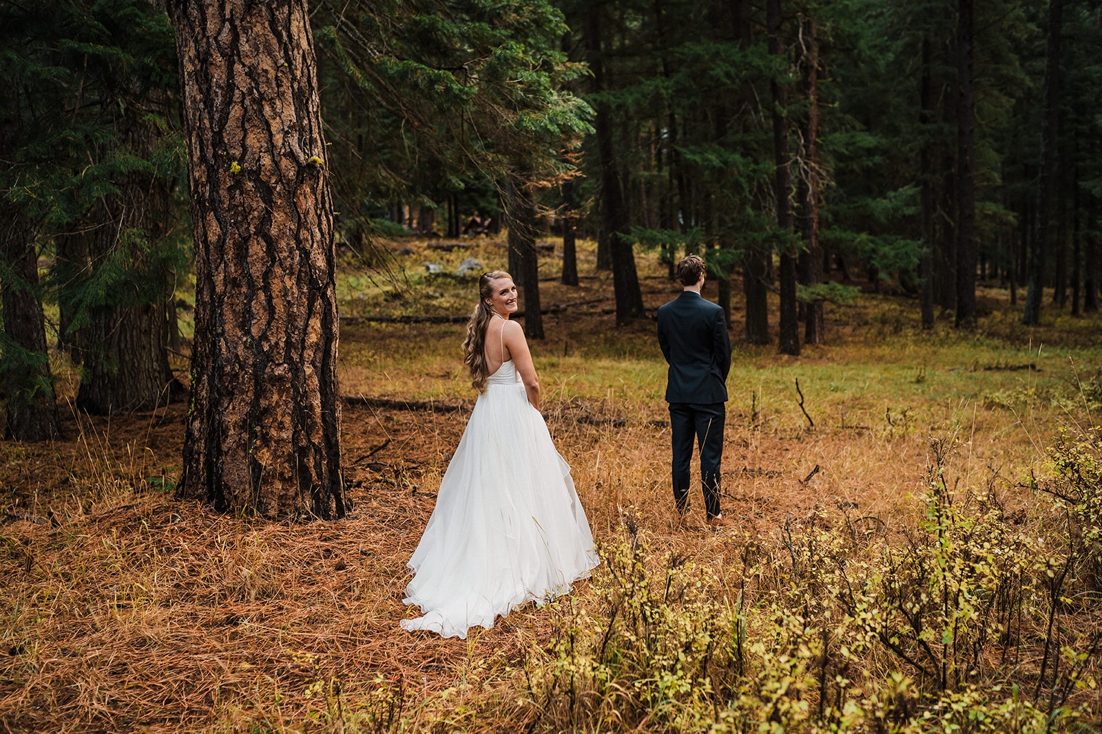 Bride turns around before doing a first look with groom outside her family cabin in Washington