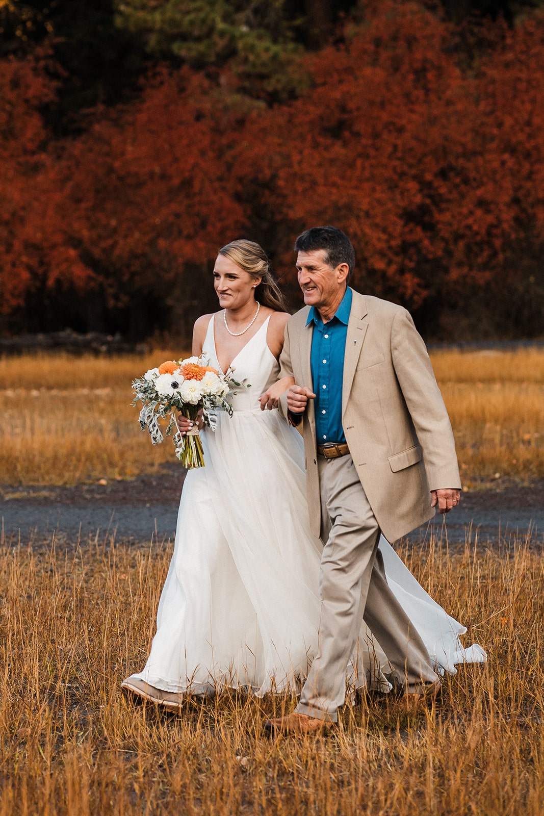 Bride walks with her father toward an outdoor fall wedding ceremony in Washington