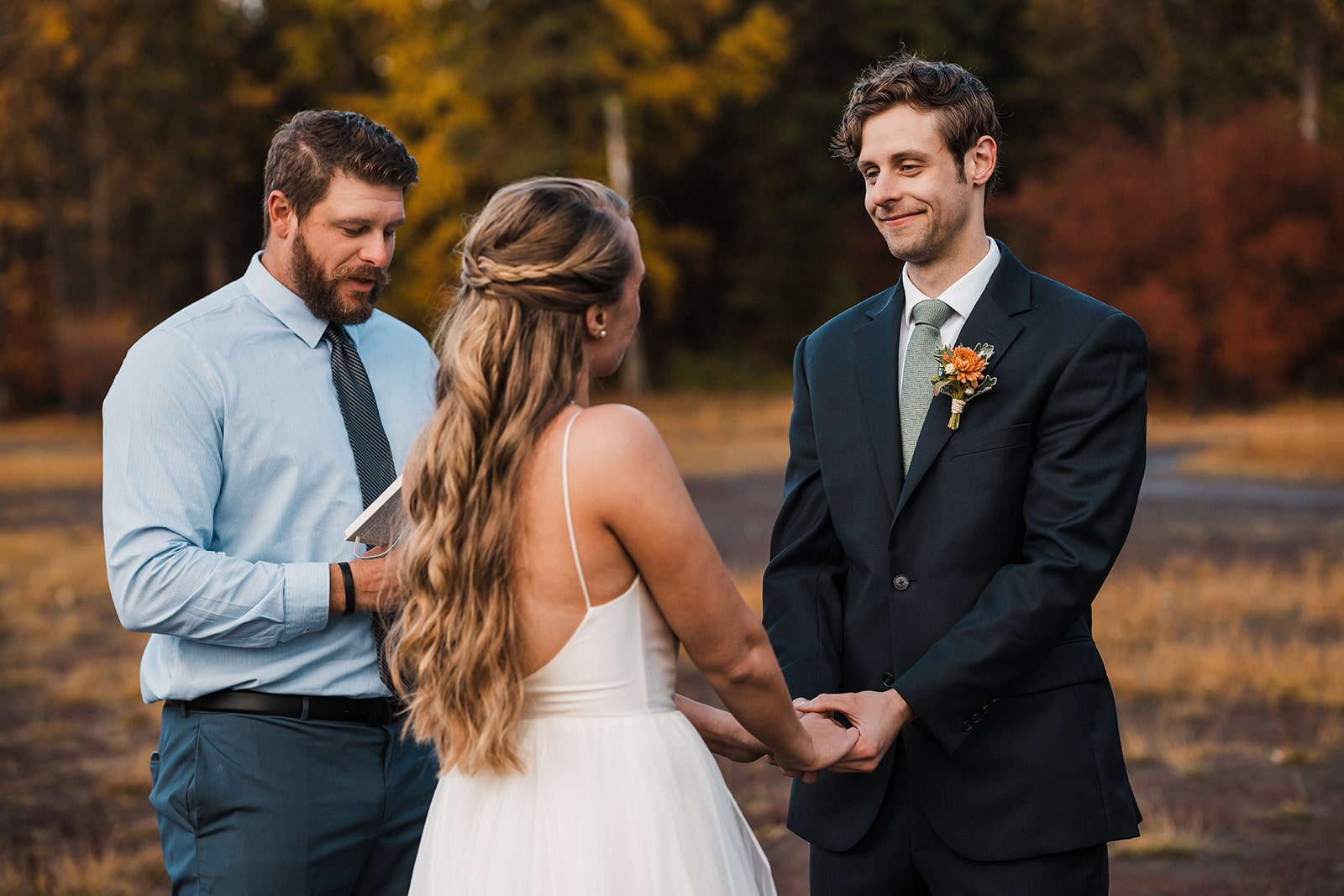 Bride and groom hold hands during their outdoor autumn wedding ceremony in Washington