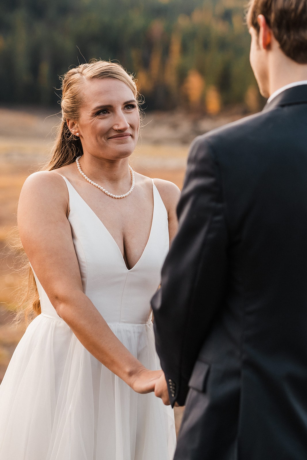 Bride and groom hold hands during their outdoor autumn wedding ceremony in Washington