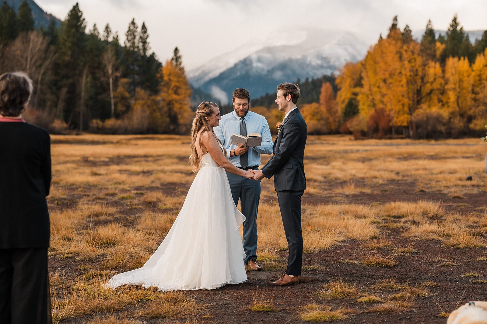 Bride and groom hold hands during their outdoor autumn wedding ceremony in Washington