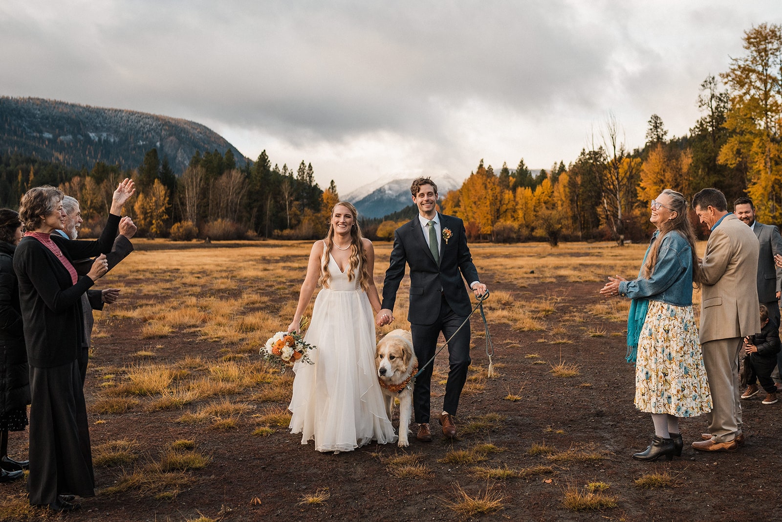 Bride and groom exit their outdoor Washington fall wedding ceremony while guests clap