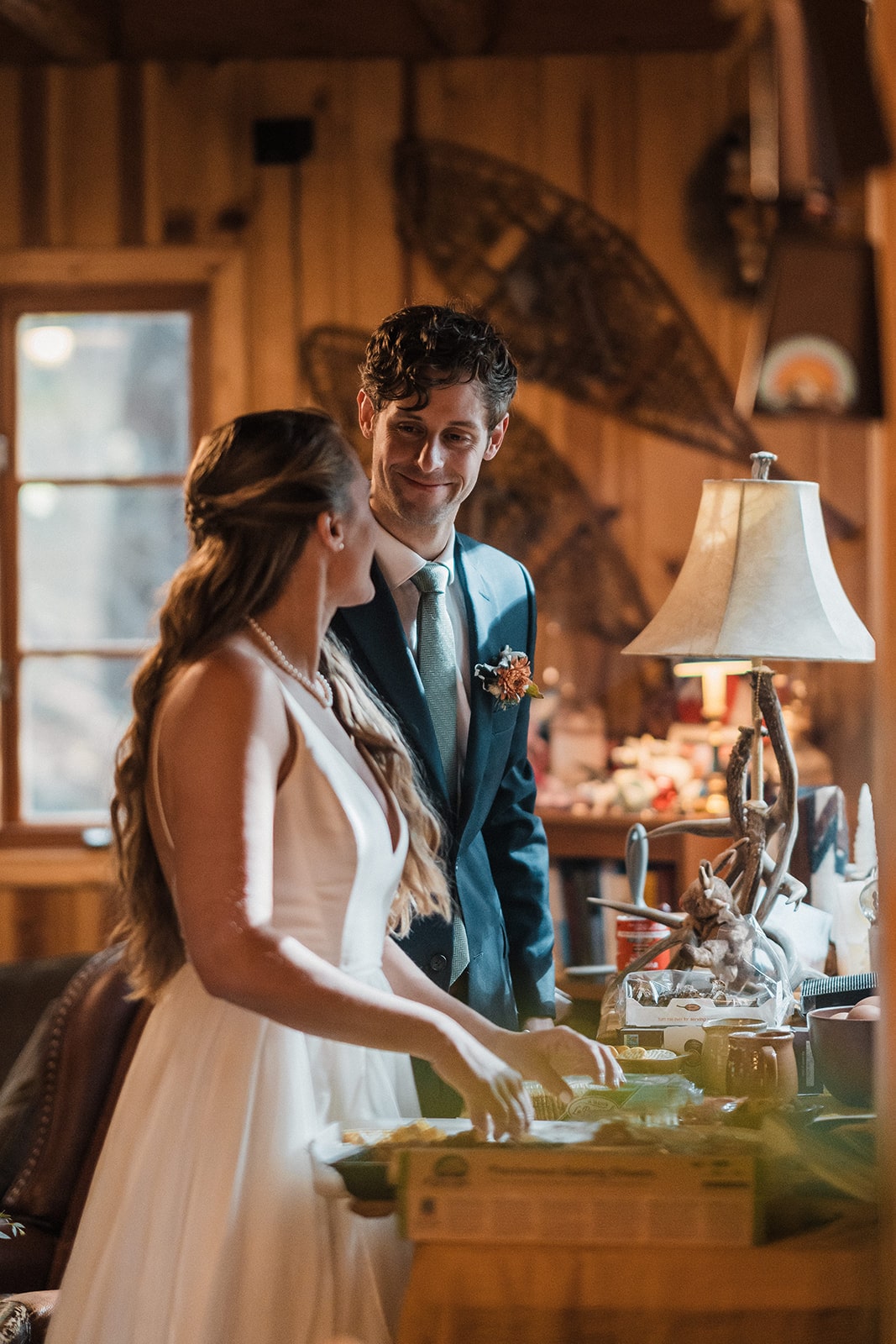 Bride and groom smile at each other while preparing brunch in their family cabin in Washington