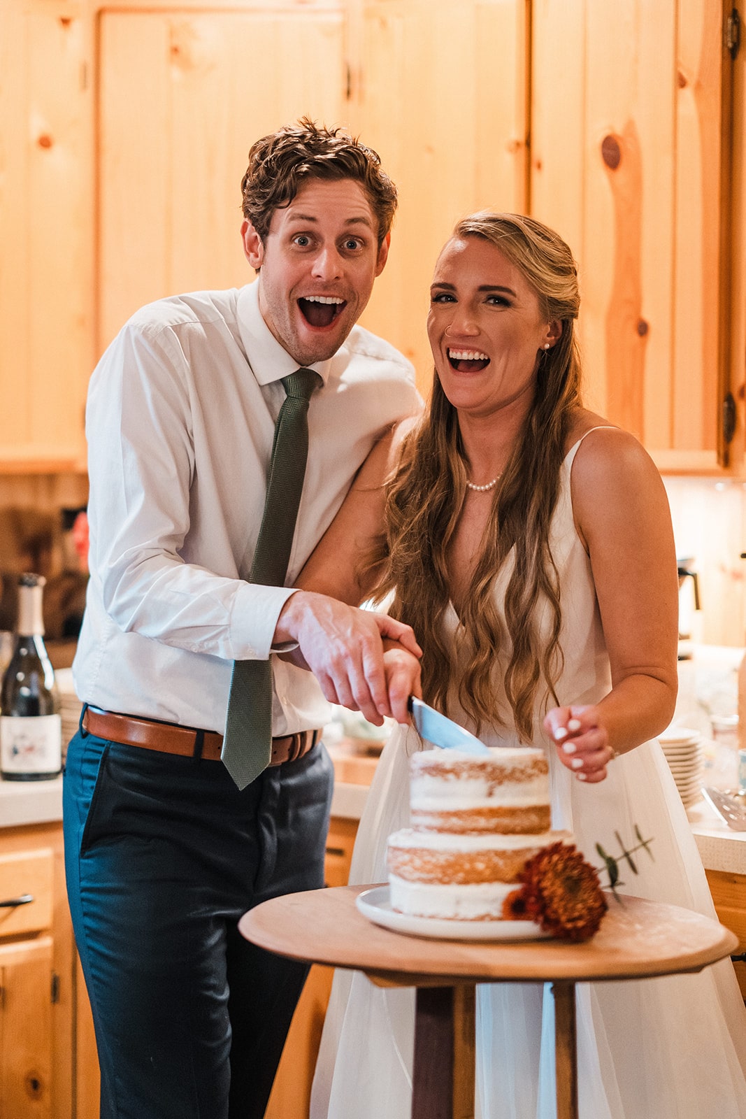 Bride and groom laugh while cutting their two tier fall wedding cake in Washington