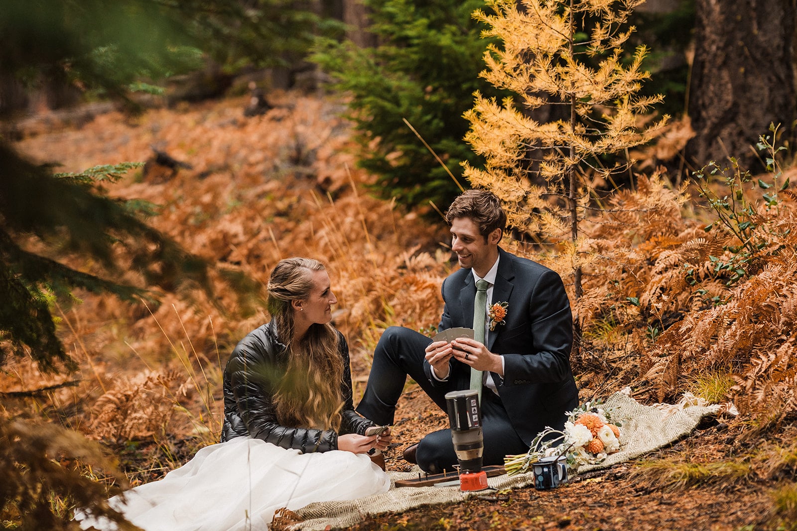 Bride and groom enjoy a fall wedding picnic in Washington surrounded by larch trees