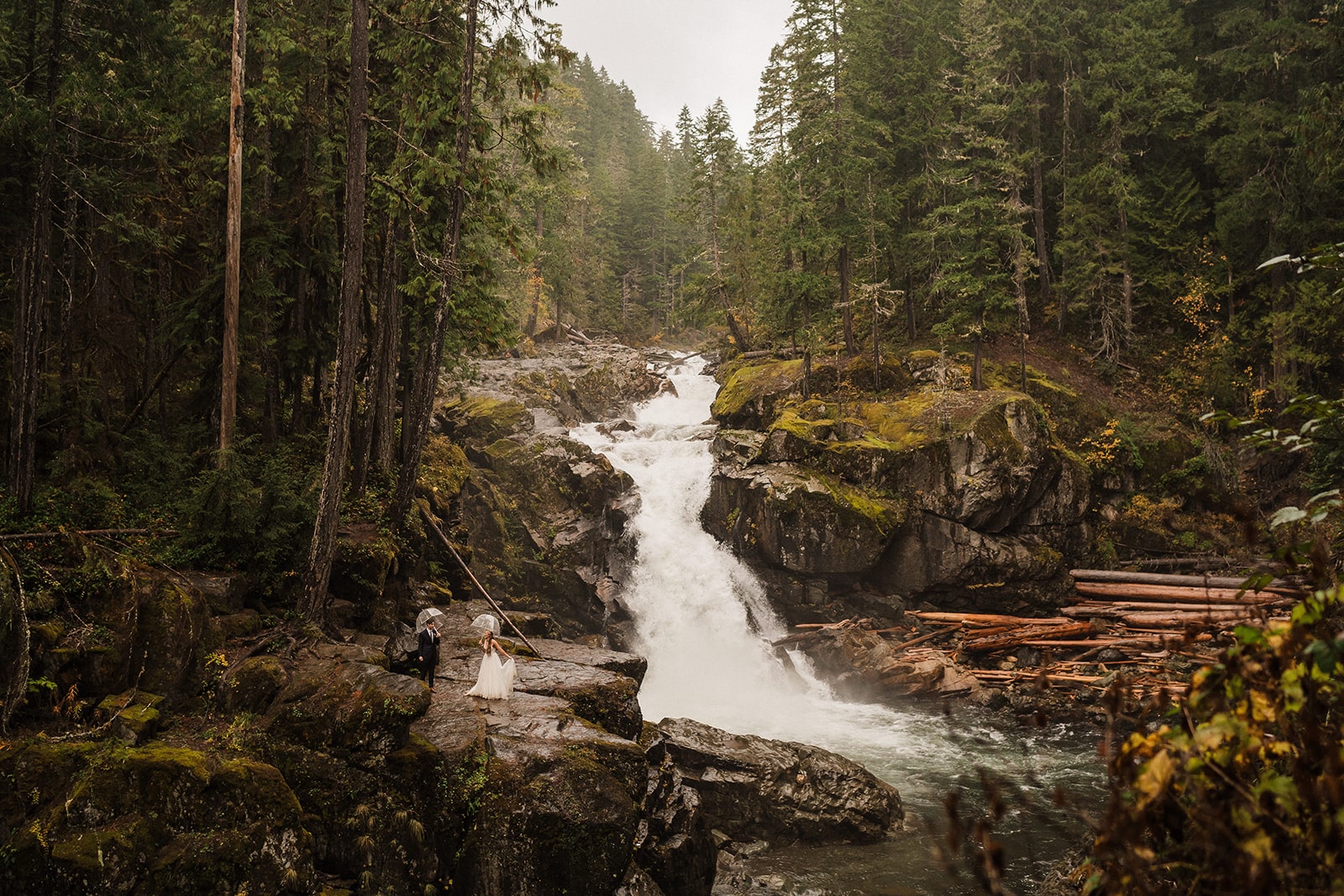 Bride and groom walk around a lower-elevation waterfall in Mt Rainier National Park during their fall wedding in Washington