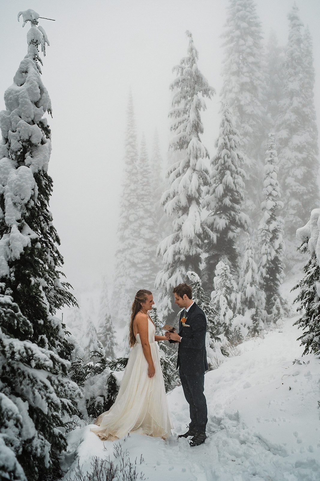 Bride and groom exchange personal vows on a snowy trail in Mt Rainier National Park