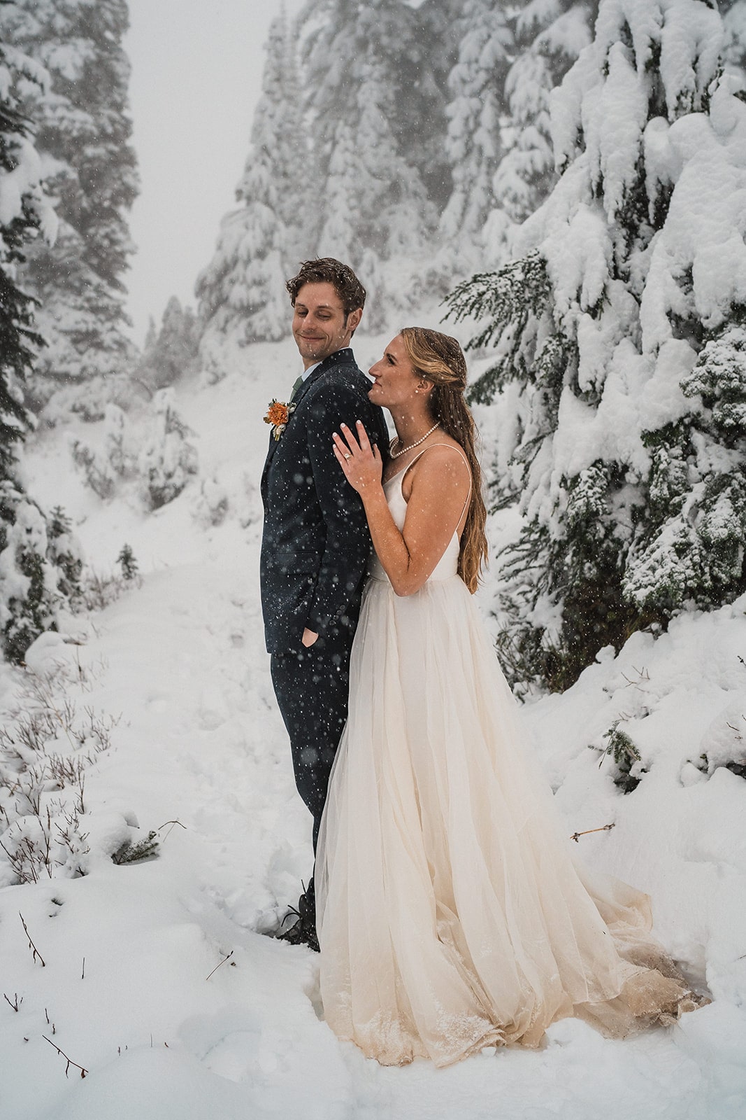 Bride and groom hug on a snowy trail in Mt Rainier National Park at the end of their fall wedding in Washington