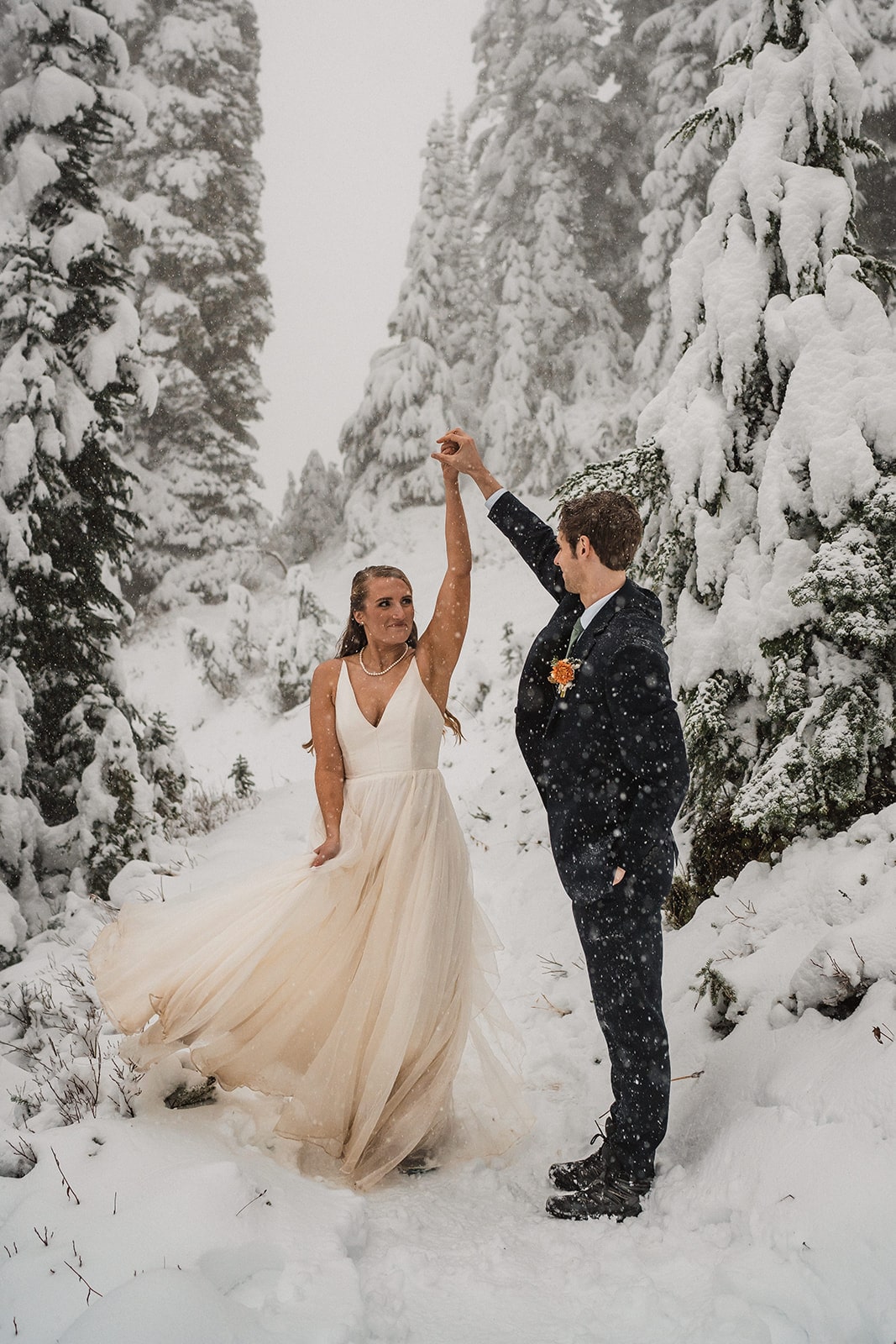 Bride and groom dance on a snowy trail in Mt Rainier National Park at the end of their fall wedding in Washington