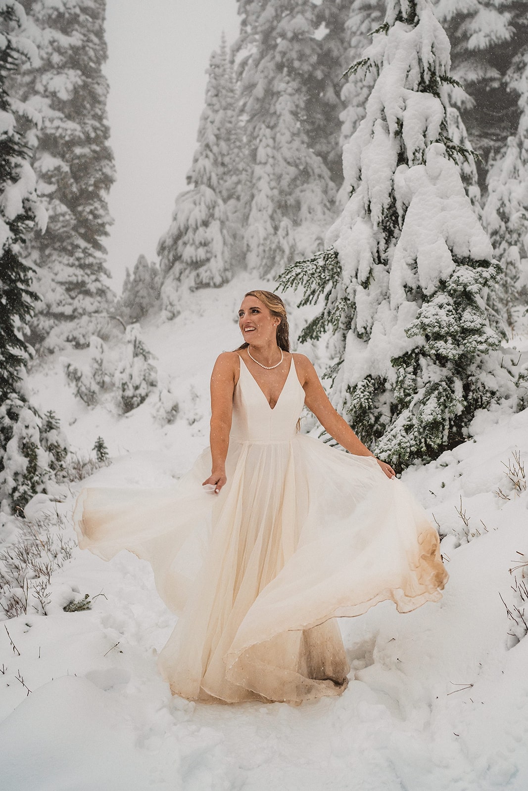 Bride dances on a snowy trail in Mt Rainier National Park at the end of their fall wedding in Washington