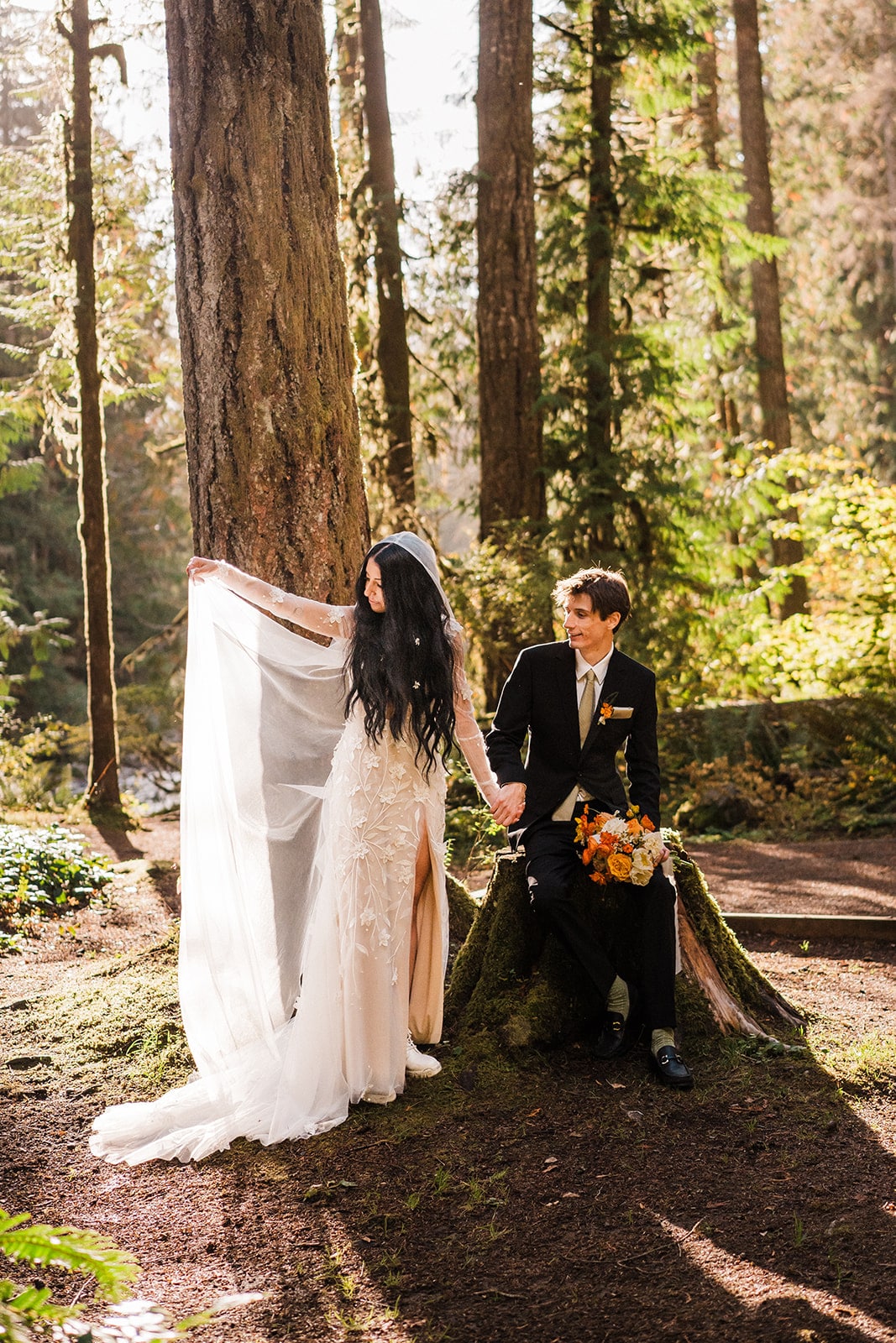 Bride lifts her veil while holding groom's hand during their forest elopement photos at Mt Baker