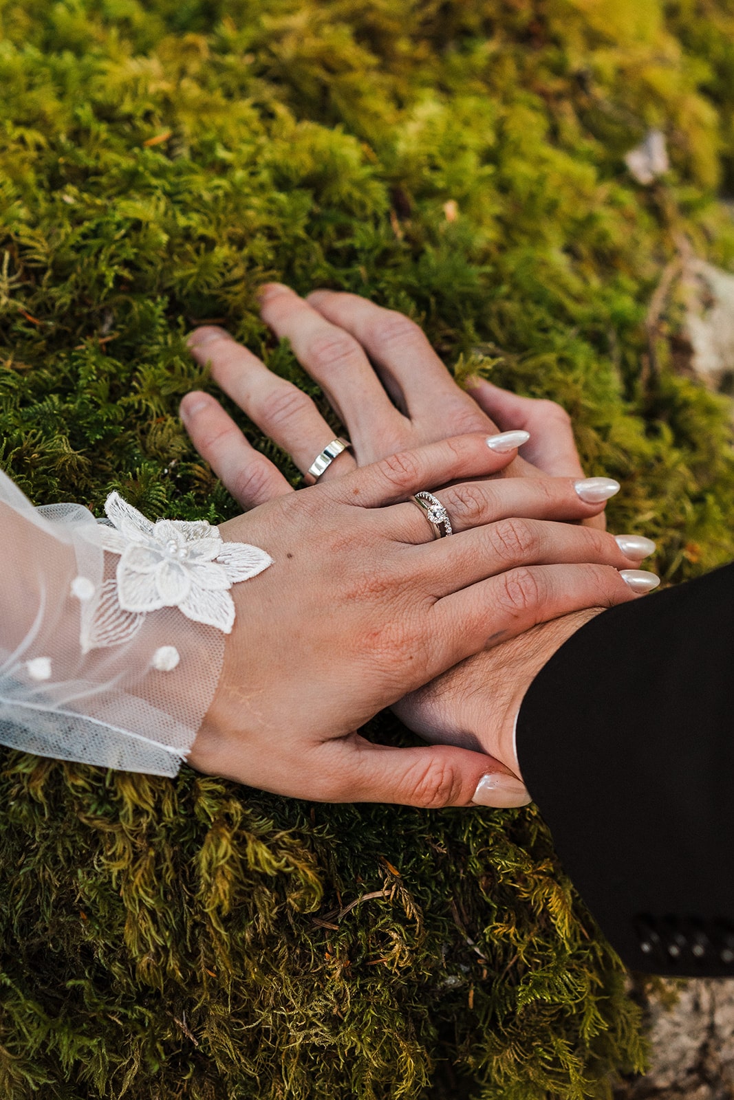 Bride and groom rest hands against a mossy rocky during their elopement photos in the forest 