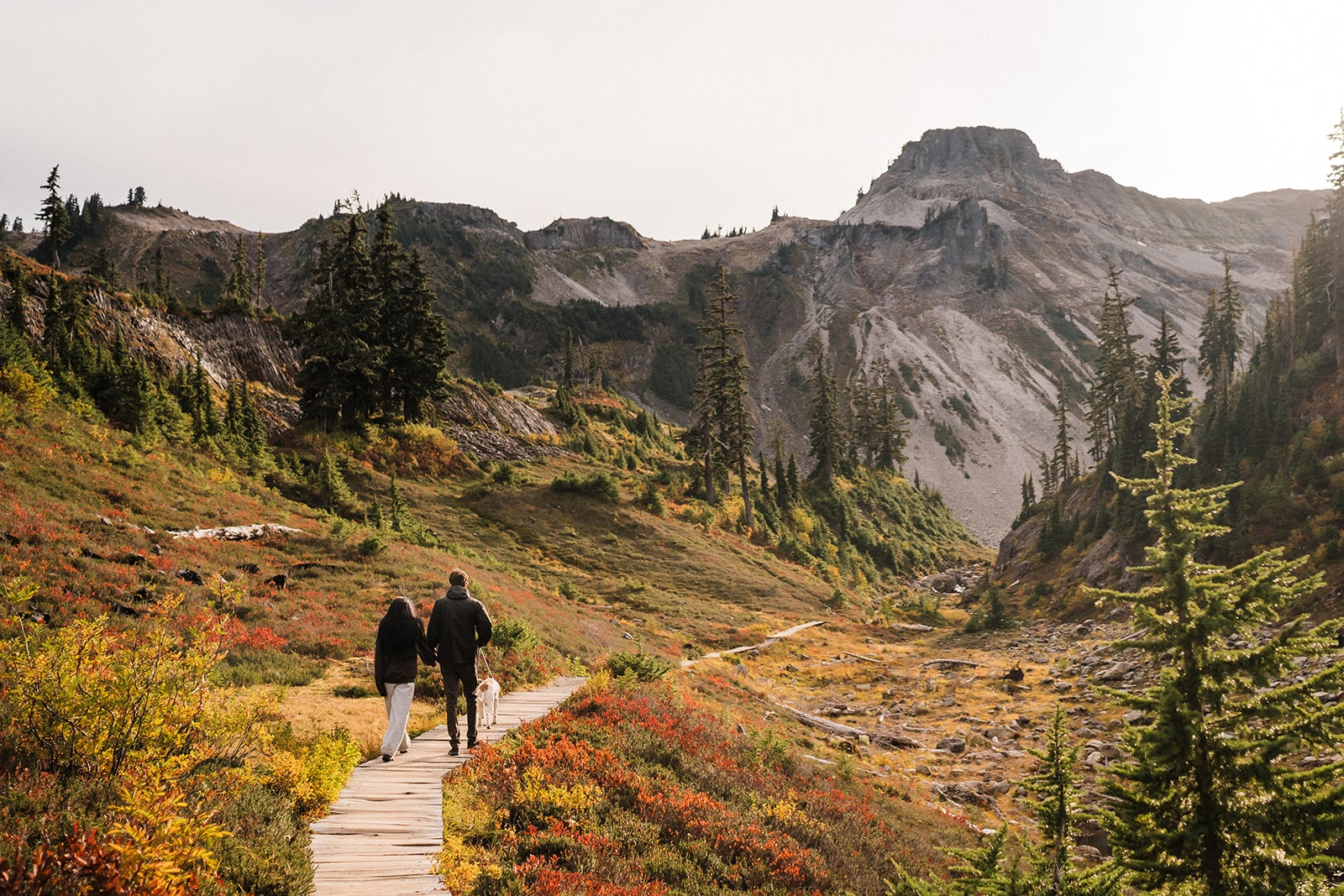 Bride and groom hold hands while walking a wood path around Bagley Lakes during their two-day elopement in Mt Baker-Snoqualmie National Forest