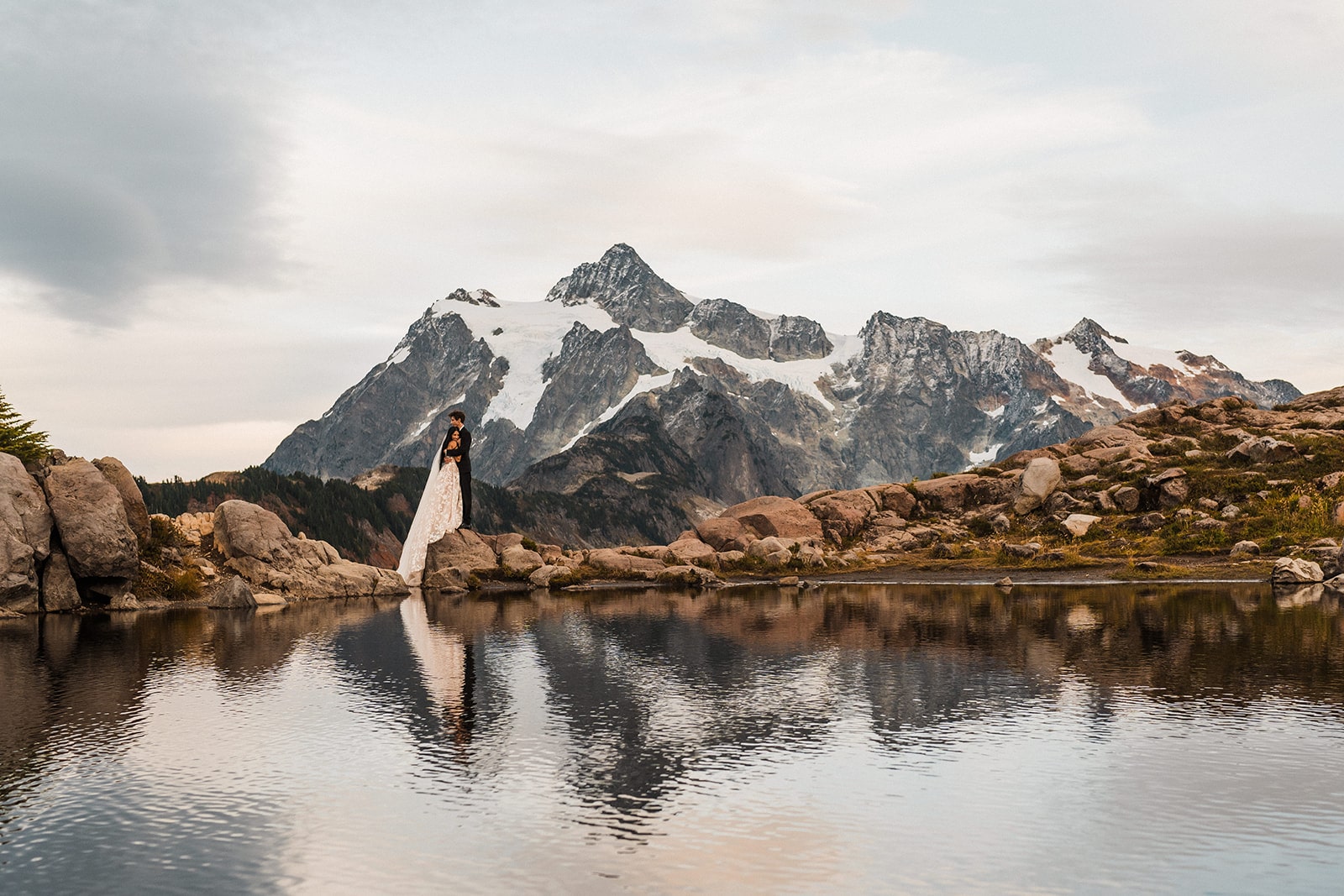 Bride and groom hug by an alpine lake during their Mt Baker elopement photos at Artist Point