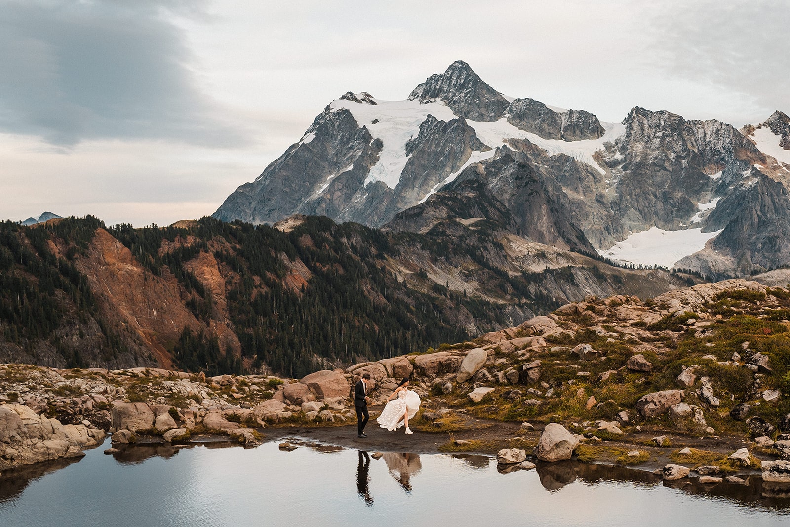 Bride and groom run around an alpine lake during their elopement photo session at Artist Point