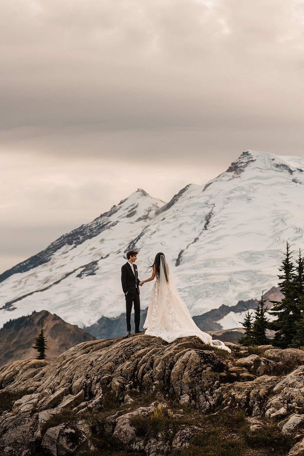 Bride and groom hold hands on a mountain trail during their Mount Baker elopement at Artist Point