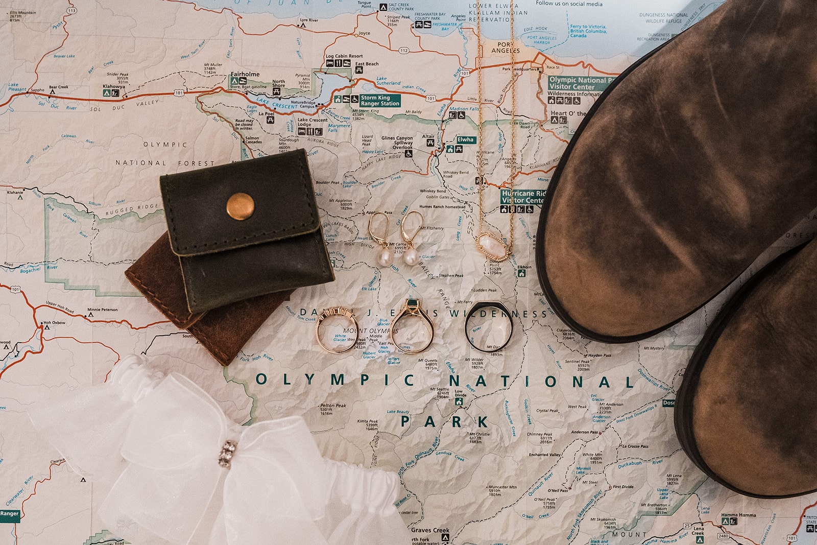 Hiking boots and wedding bands rest on top of a Washington map of Olympic National Park