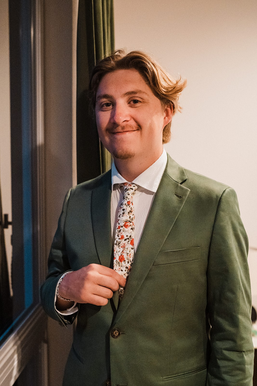 Groom wears a green suit with a floral tie for his national park elopement on the Olympic Peninsula