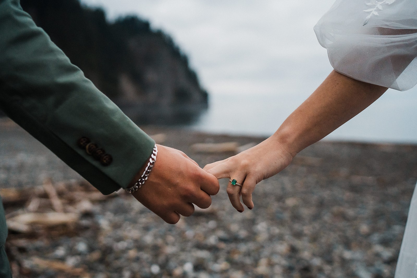 Bride and groom hold hands on a rocky beach during their Washington national park wedding