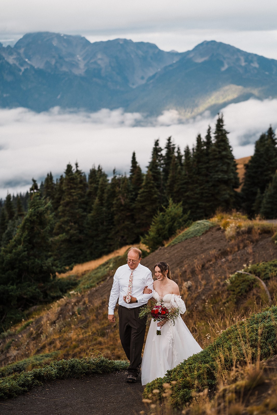 Bride smiles while walking down an outdoor wedding aisle with her father at her national park elopement