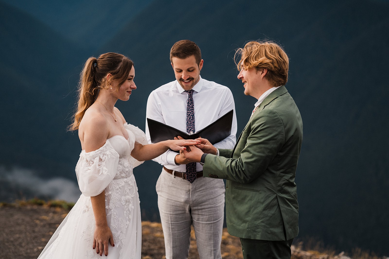 Groom puts ring on bride's finger during their national park wedding ceremony at Hurricane Ridge