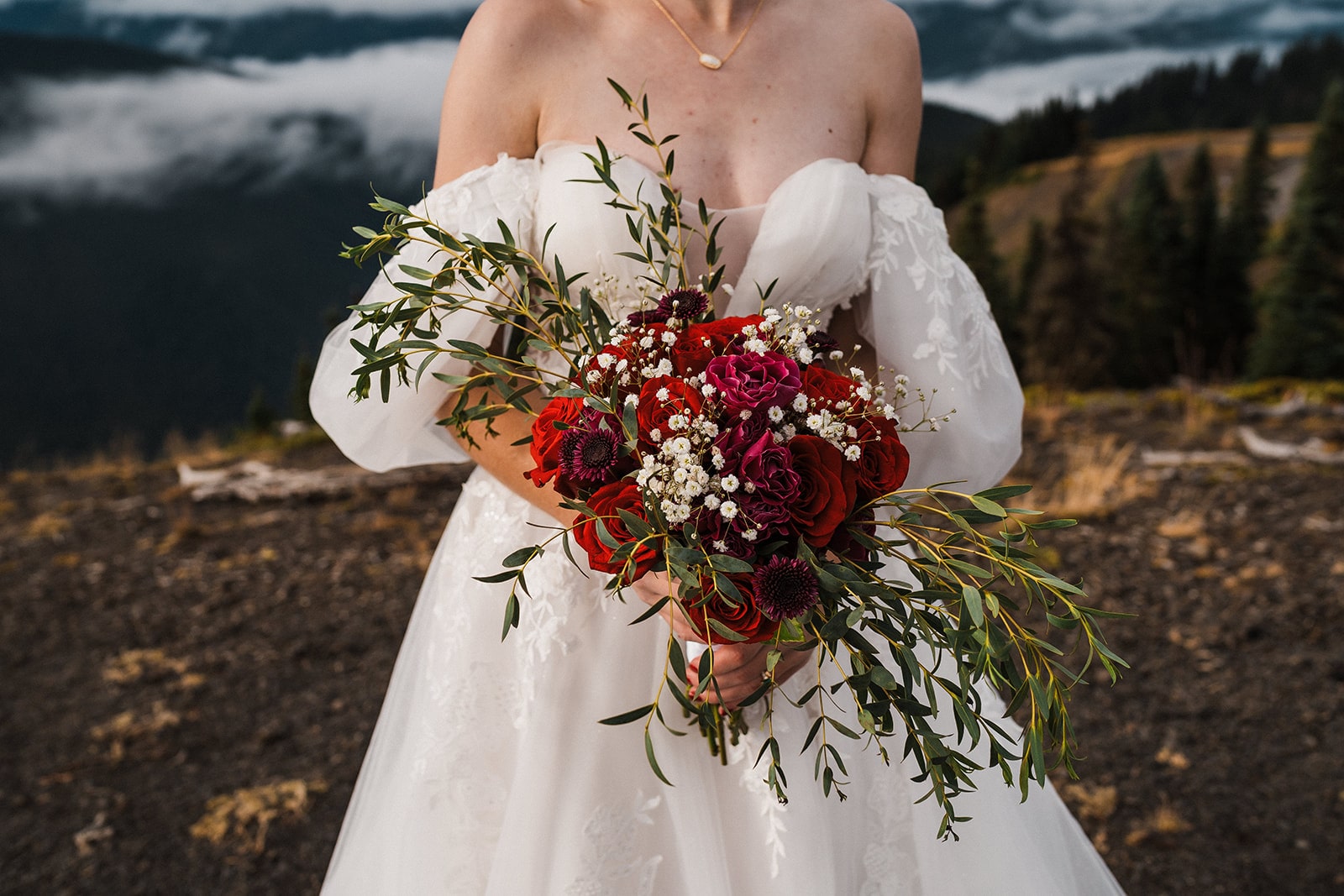 Bride holds a bouquet of red flowers during her national park wedding in Olympic National Park