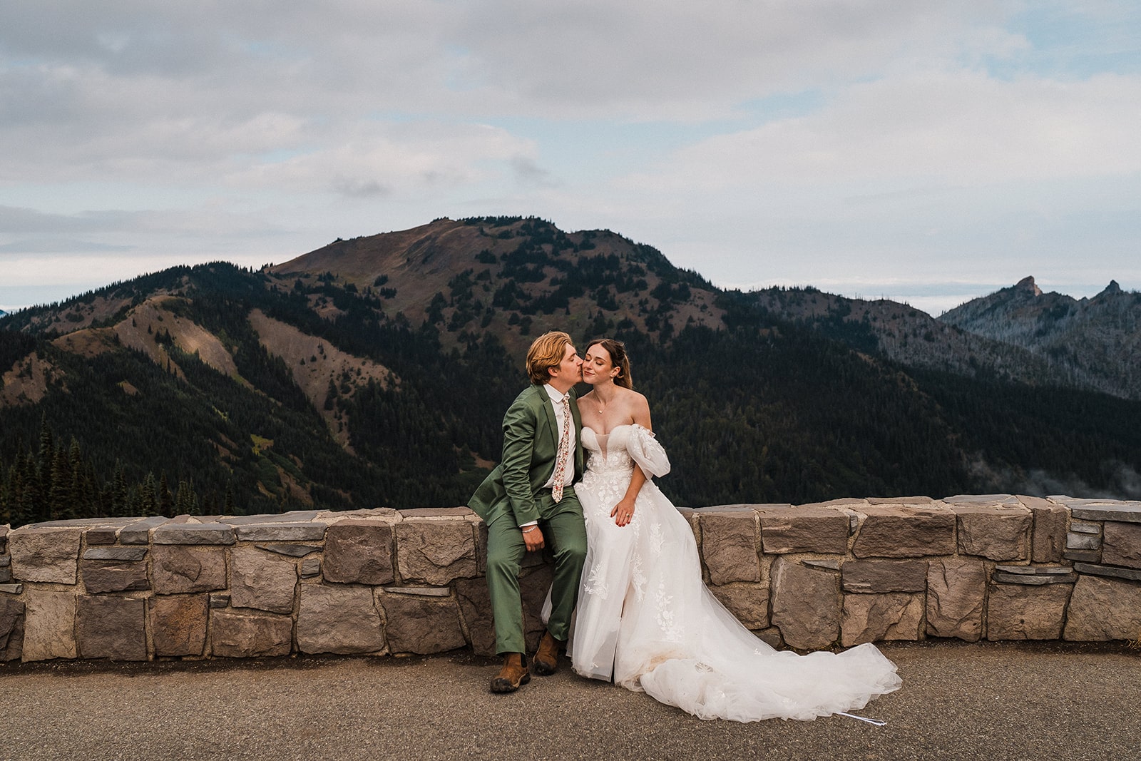 Groom kisses bride on the cheek while resting at their Hurricane Ridge elopement