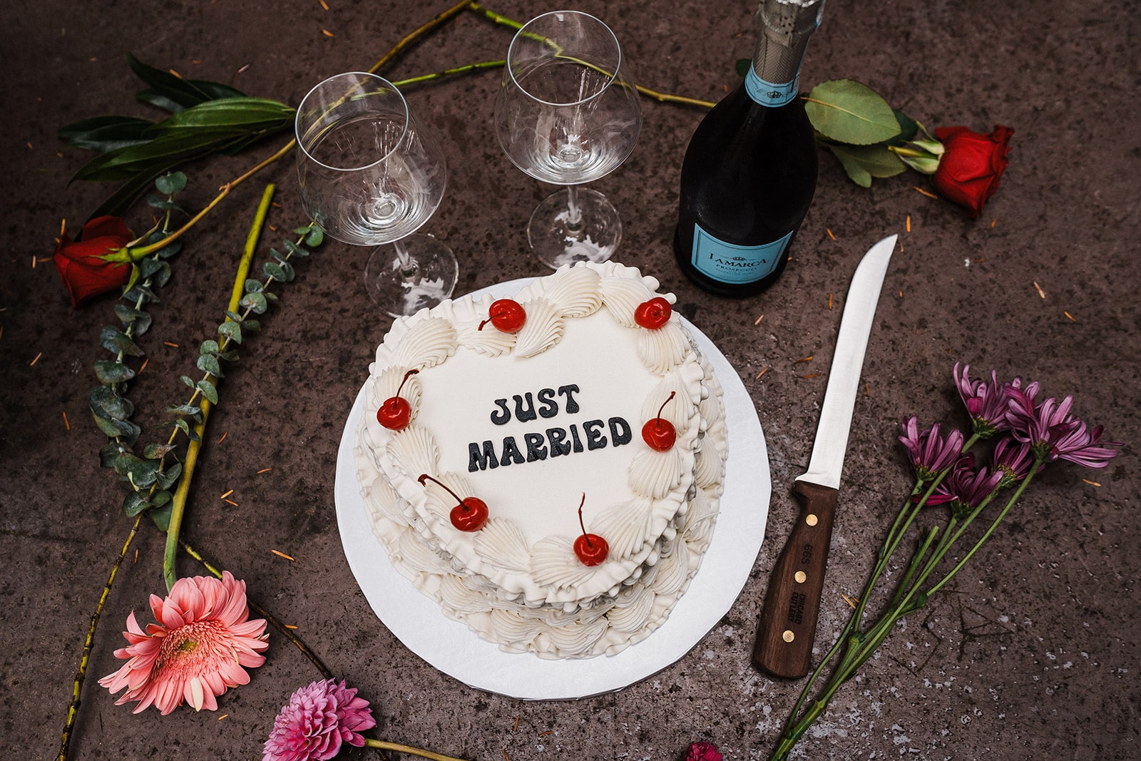 White frosted heart cake with maraschino cherries and "Just Married" written in black icing