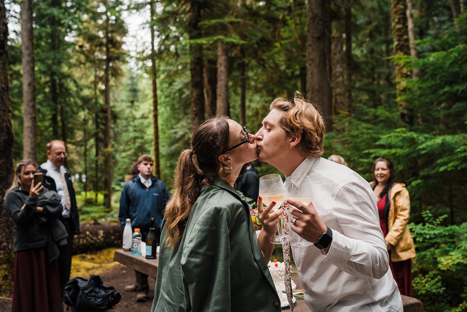 Bride and groom kiss at their brunch elopement reception in the forest 