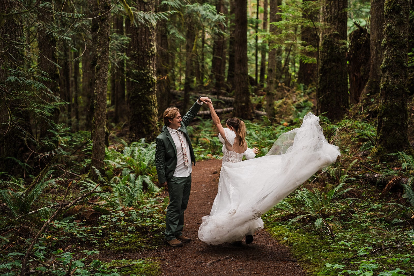 Groom twirls bride around on a forest trail during their national park elopement on the Olympic Peninsula