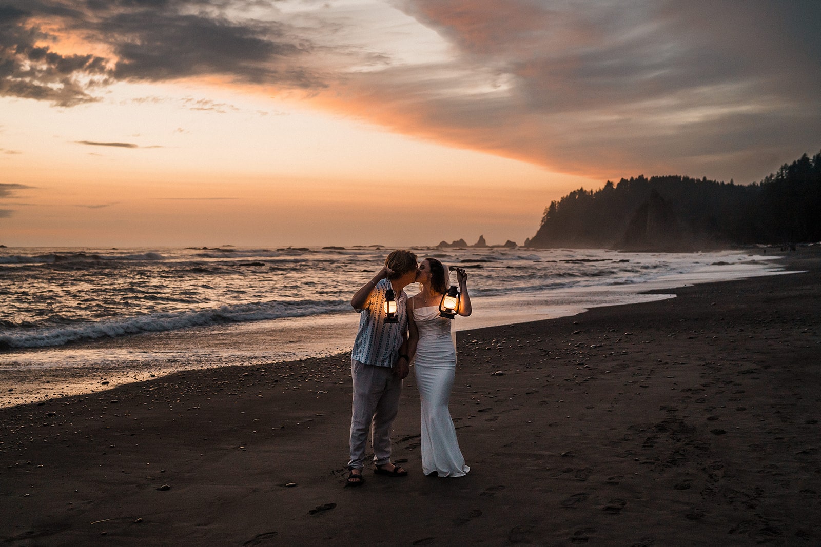 Bride and groom hold lanterns and kiss during their sunset adventure photos at Rialto Beach