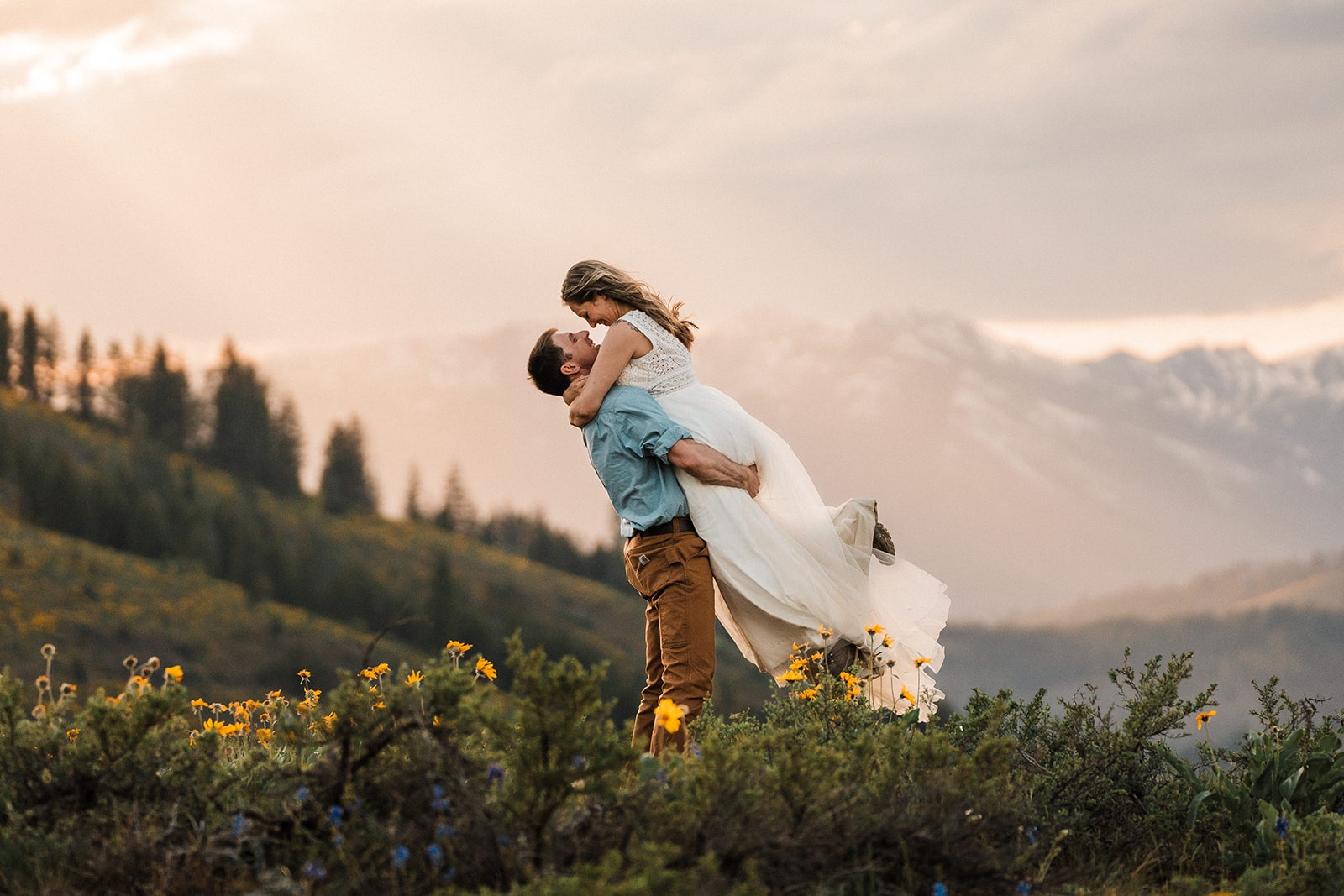 Groom lifts bride for a kiss on a mountain trail at sunset during their elopement in Eastern Washington
