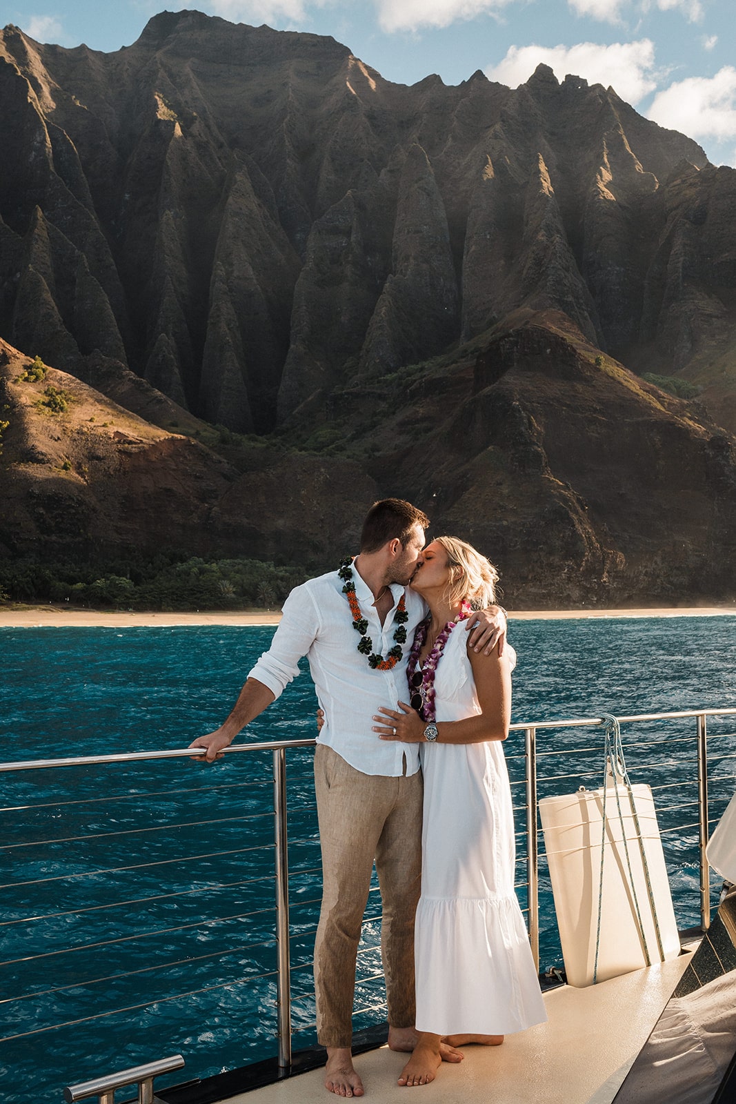Couple kisses on the rail of a catamaran boat tour on the Na Pali Coast in Kauai