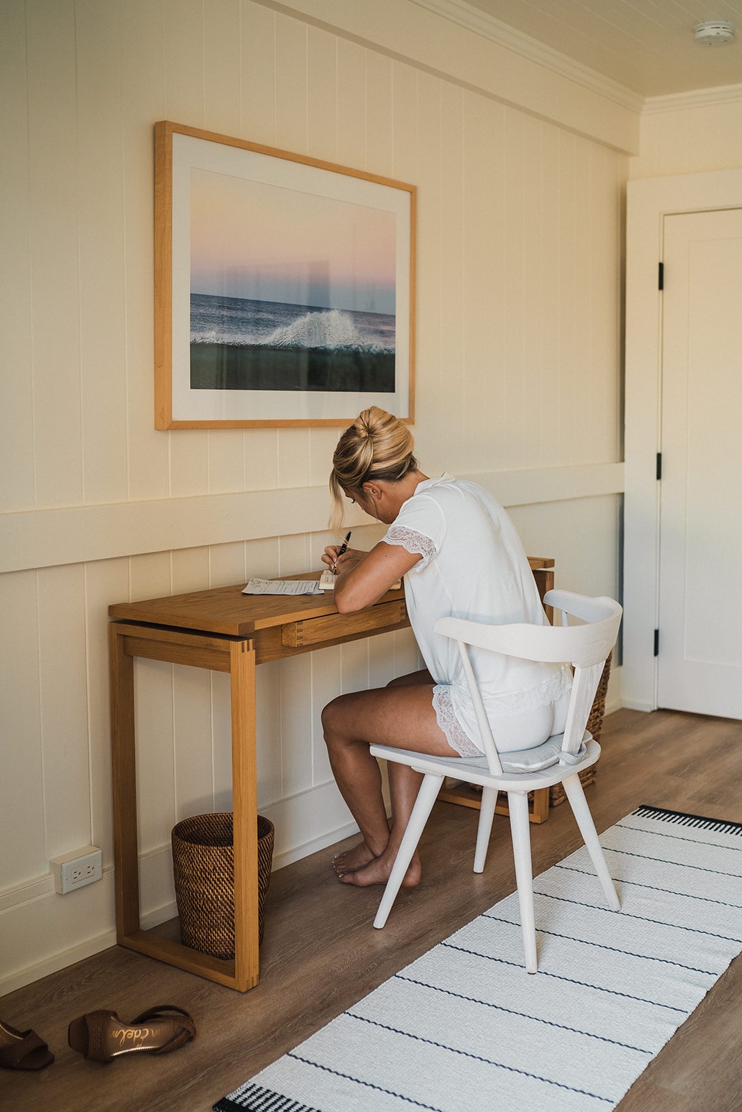 Bride sits at a desk writing personal vows while getting ready for her Kauai micro wedding.
