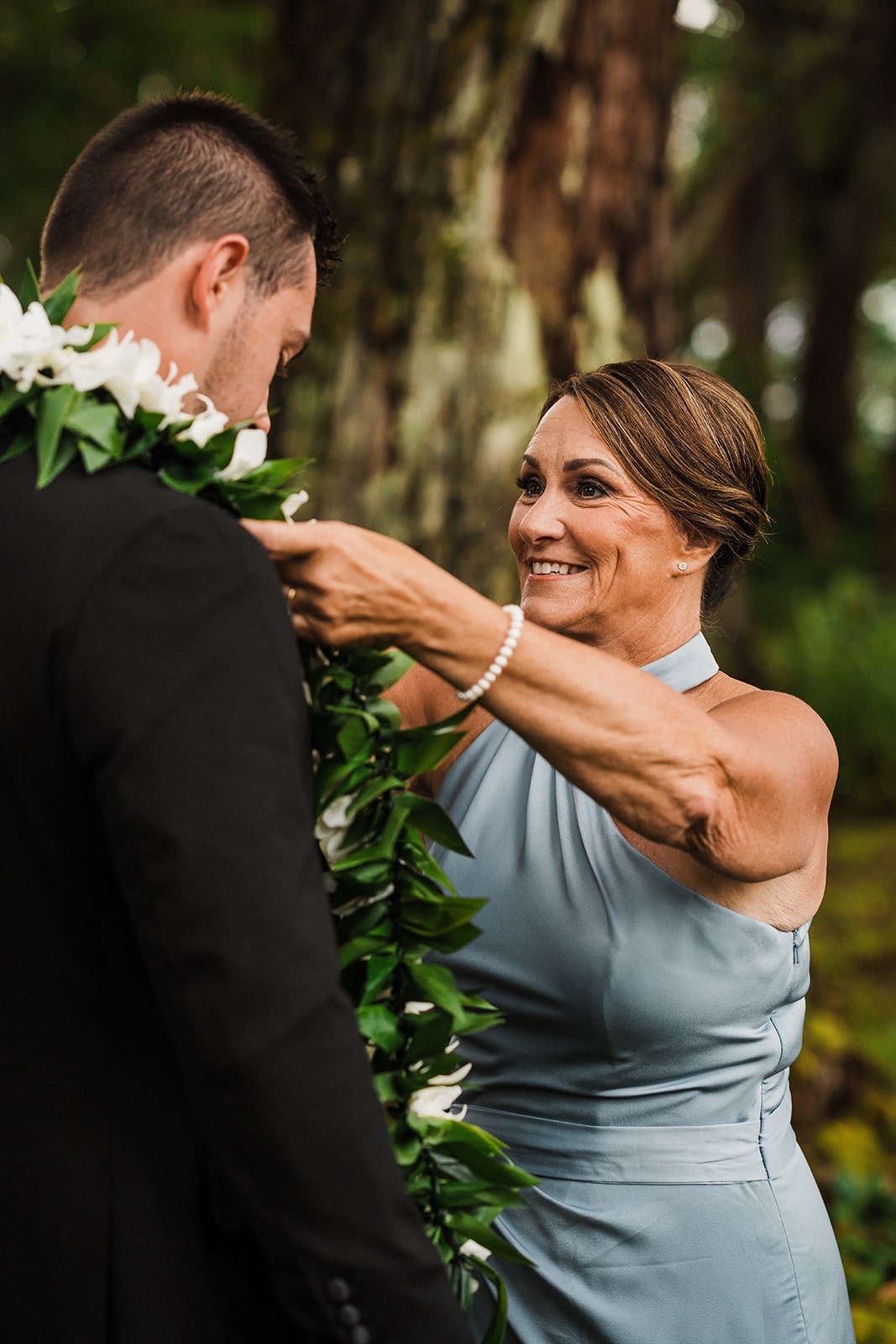 Groom's mother adjusts his lei while getting ready for his Kauai micro wedding ceremony.